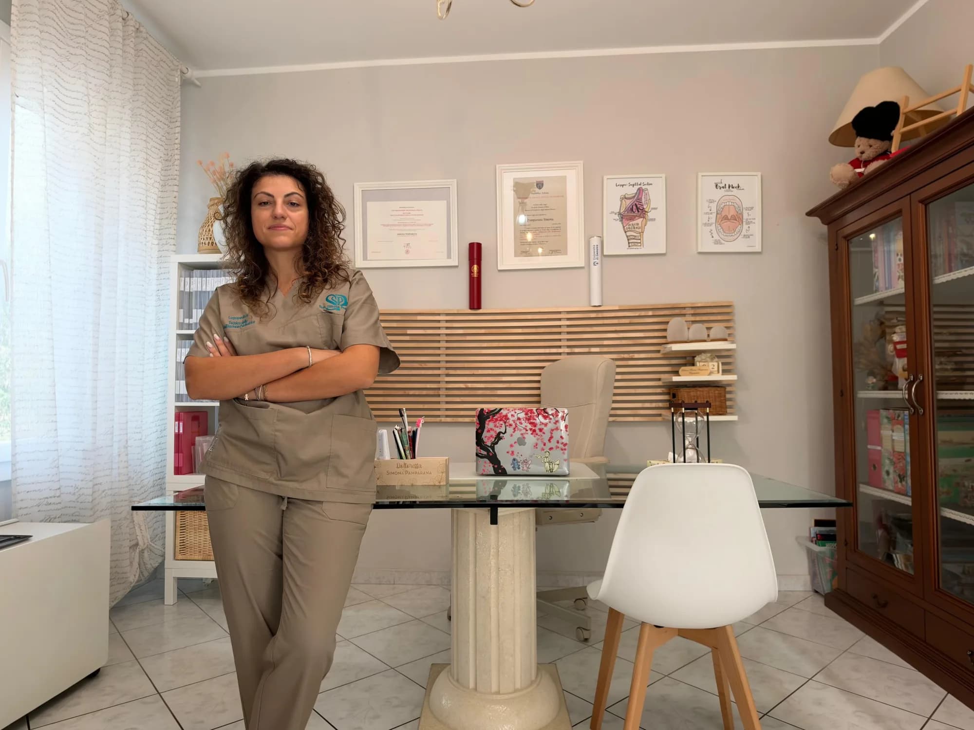 Simona Pamparana in piedi nel suo studio, a braccia incrociate, davanti alla scrivania